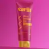 Vibrant pink Curlit leave-in conditioner tube with yellow cap, designed for wavy hair, promoting biggest flex, with silicone and paraben-free for moisturized, frizz-free, defined waves.
