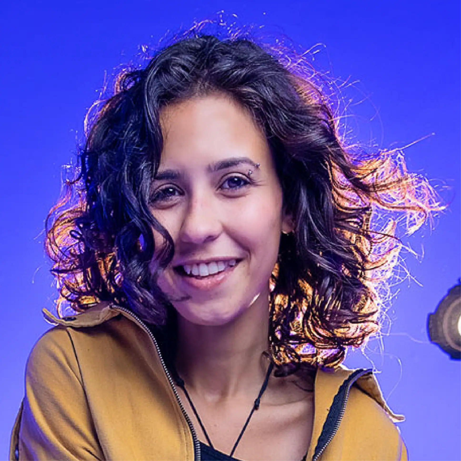 Curly hair woman smiling with vibrant lighting background, showcasing natural textured curls for hair styling and beauty inspiration.