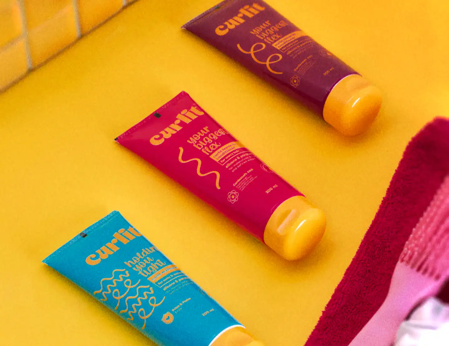 Vibrant hair curl cream tubes on a yellow background, featuring Curlit brand for perfect curls and textured hair care.